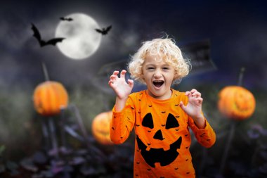 Cadılar Bayramı kostümlü çocuk. Çocuklar şeker mi şaka mı? Balkabağı feneri takmış küçük bir çocuk. Aile kutlaması. 