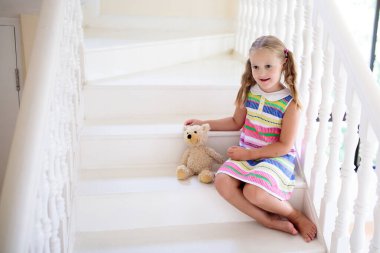 Beyaz Saray 'da merdivenlerde yürüyen bir çocuk. Küçük kız güneşli merdivenlerde oynuyor. Aile yeni bir eve taşınıyor. Modern merdivenlerde çocuk merdivenleri tırmanıyor. Giriş salonu mu, oturma odası mı? Bebek için ev güvenliği.