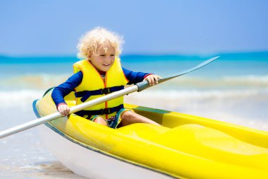 Çocuklar okyanusta kayak yapıyor. Tropikal denizde kanodaki çocuklar. Genç bir çocukla aktif tatil. Güzel bir sahilde kanoda küçük bir çocuk. Anaokulu çocuğuyla tatil aktivitesi. Aile suyu eğlencesi.