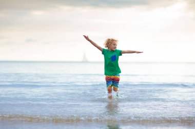 Tropik plajda oynayan bir çocuk. Deniz kıyısındaki küçük erkek bebek. Aile yaz tatili. Çocuklar su ve kum oyuncaklarıyla oynuyor. Okyanus ve ada eğlencesi. Asya 'da küçük çocuklarla seyahat et..