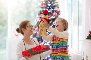 Noel ağacında aile açılış hediyesi. Çocuklar Noel sabahı hediyelerini açarlar. Anne ve küçük çocuk dekore edilmiş oturma odasında. Kış tatili Ebeveynler ve çocuklar birbirlerine hediye verirler..