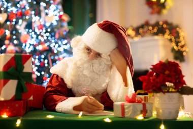 Noel Baba Noel arifesinde hediye getiriyor. Xmas ağacının altında hediyeler. Şömine ve ışıklarla dekore edilmiş oturma odası. Evde kış tatili kutlaması.