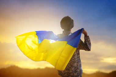 Ukrayna 'da savaş. Ukrayna bayrağı taşıyan asker evine dönüyor. Zaferi kutlayan vatansever. Yaşasın Ukrayna, yaşasın kahramanlar. Ordu savaştan sonra şehri ele geçirdi..