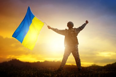 Ukrayna 'da savaş. Ukrayna bayrağı taşıyan asker evine dönüyor. Zaferi kutlayan vatansever. Yaşasın Ukrayna, yaşasın kahramanlar. Ordu savaştan sonra şehri ele geçirdi..