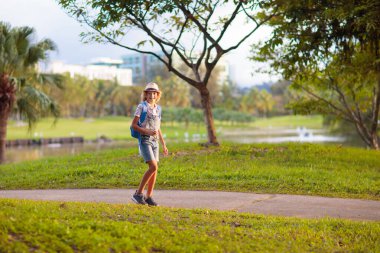 Çocuklar dışarıda oynar ve doğayı keşfederler. Güneşli parkta oynayan çocuklar. Çocuklar güzel şehir parkında yürürler ve koşarlar. Sıcak yaz gününde koşan bir çocuk. Çocuk çevreyi keşfediyor. Genç kaşif macerası.