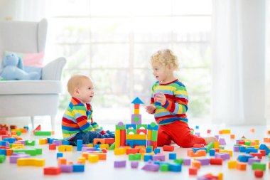 Kids ahşap oyuncak legolarla oynamak. Çocuklar için eğitici renkli oyuncaklar. Erkek ve kız anaokulu Oda büyük pencere ile oynamak. Kule ile rainbow blok bina çocuk. Çocuk evde.