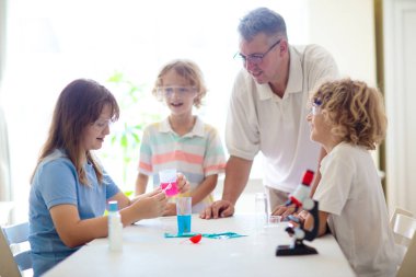 Okul fen dersi. Kimya dersindeki öğrenciler. Çocuklar kimyasal reaksiyonu izliyor. Öğretmen ve ilkokul çocukları sınıfta. Birinci sınıf çocuk bilimsel deney yapıyor. Kök kulüp.