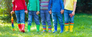 Çizmeli çocuklar. Renkli lastik çizmeler ve sonbahar ceketleri giymiş bir grup anaokulu çocuğu. Yağmurlu bir sonbahar için ayakkabılar. Çocuk ve bebek için ayak giysisi. Çizmeli yeni yetme. Gökkuşağı çizmeleri. Çocuk modası