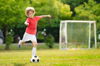 Çocuk futbol oynuyor. Çocuklar dışarıda futbol oynarlar. Küçük çocuk yaz parkında topa vuruyor. Küçük çocuklar için sağlıklı bir aktivite. Okul spor kulübü takımı. Futbol Küçükler Ligi.