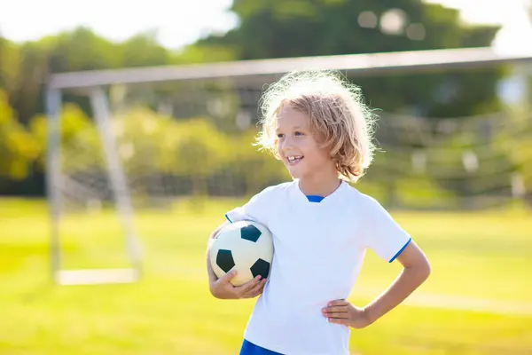 stock image Kids play football on outdoor field. England team fan. Children score a goal at soccer game. Boy in UK jersey kicking ball. School football club. Sports training for young player.
