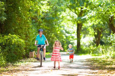 Yaz parkında bisiklet süren bir çocuk. Okula bisikletle gidiliyor. Güneşli bir akşamda bisiklete binen çocuk. Çocuk dışarıda egzersiz yapıyor. Sağlıklı açık hava spor aktiviteleri. Çocukların güvenliği ve korunması için miğfer.