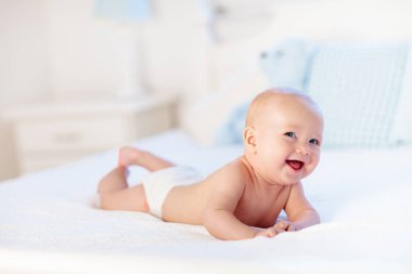 Erkek bebek bezi beyaz güneşli yatak odasında. Yeni doğan çocuk yatakta rahatlatıcı. Kreş çocuklar için. Tekstil ve çocuklar için yatak. Aile sabah evde. Oyuncak ayı ile mide süre içinde yeni doğmuş çocuk.
