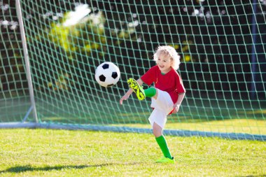 Çocuklar dışarıda futbol oynarlar. Portekiz takım taraftarları. Çocuklar futbol maçında gol attılar. Portekiz formalı ve kramponlu çocuk topa vuruyor. Futbol kulübü sahası. Genç oyuncu için spor eğitimi.
