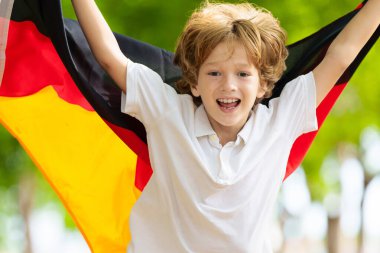 Çocuk Almanya bayrağıyla koşuyor. Küçük Alman çocuk ülke takımı için tezahürat yapıyor. Deutschland taraftarları spor sahasında takımın maçını izliyorlar. Aile ulusal günü kutluyor. Şampiyonluk maçı.