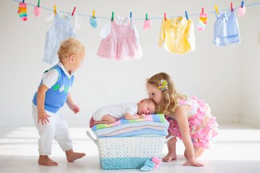 Yeni doğmuş bebek çamaşır ipinde temiz havlu yığınının üzerinde. Çocuklar için çamaşır. Havluyla banyo yaptıktan sonra doğan yeni çocuk. Aile çamaşırları. Çocuklar yeni doğan kardeşleriyle oynarlar. Bebek kıyafetleri.