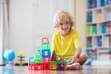 Çocuk manyetik yapı taşlarıyla oynuyor. Küçük çocuk kule inşa ediyor. Çocuklar için eğitici oyuncaklar. Küçük çocuklar için inşaat oyuncakları. Geometri ve matematik oyunu. Okul öncesi eğlencesi.