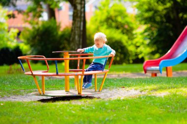 Çocuklar doğayı keşfeder. Çocuklar güneşli parkta oynarlar. Çocuk güzel bir yaz parkında oyun parkında. Aktif aile için açık hava eğlencesi. Çocuk sallanıyor ve kayıyor..
