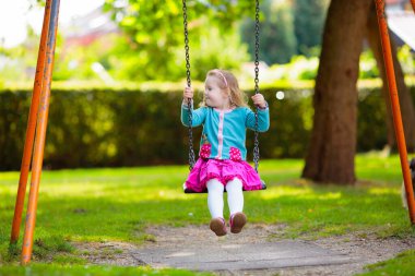 Çocuklar doğayı keşfeder. Çocuklar güneşli parkta oynarlar. Çocuk güzel bir yaz parkında oyun parkında. Aktif aile için açık hava eğlencesi. Çocuk sallanıyor ve kayıyor..