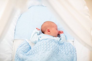 Yeni doğan bebek yatakta. Yeni doğan çocuk mavi örgü battaniye altında uyuyor. Çocuk uyku. Çocuklar için yatak takımları. Bebek yatakta uyuyor. Sağlıklı çocuk doğumdan kısa bir süre sonra. Kablo Tekstil Örme.