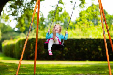 Çocuklar doğayı keşfeder. Çocuklar güneşli parkta oynarlar. Çocuk güzel bir yaz parkında oyun parkında. Aktif aile için açık hava eğlencesi. Çocuk sallanıyor ve kayıyor..