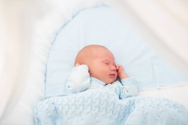 Yeni doğan bebek yatakta. Yeni doğan çocuk mavi örgü battaniye altında uyuyor. Çocuk uyku. Çocuklar için yatak takımları. Bebek yatakta uyuyor. Sağlıklı çocuk doğumdan kısa bir süre sonra. Kablo Tekstil Örme.