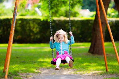 Çocuklar doğayı keşfeder. Çocuklar güneşli parkta oynarlar. Çocuk güzel bir yaz parkında oyun parkında. Aktif aile için açık hava eğlencesi. Çocuk sallanıyor ve kayıyor..