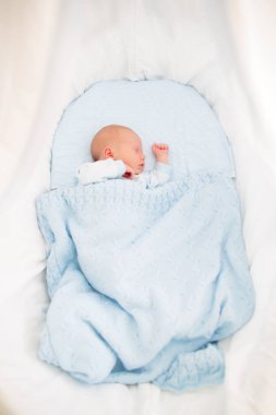 Yeni doğan bebek yatakta. Yeni doğan çocuk mavi örgü battaniye altında uyuyor. Çocuk uyku. Çocuklar için yatak takımları. Bebek yatakta uyuyor. Sağlıklı çocuk doğumdan kısa bir süre sonra. Kablo Tekstil Örme.