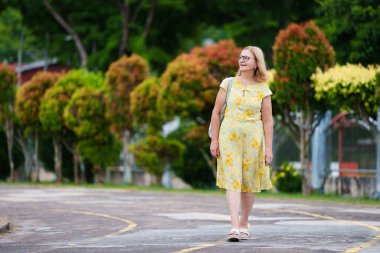 Şehir caddesinde cep telefonu olan yaşlı bir kadın. Güneşli yaz şehrinde güzel, şık bir bayan yürüyor. Emeklilik süresince seyahat edin ve dinlenin. Kadın arıyor ve cep telefonundan mesaj atıyor..