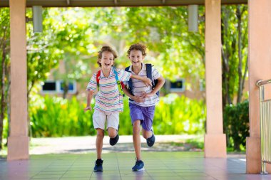 Çocuk okula döndüğü için mutlu. Okul çocukları için yaz tatilinin sonu ya da başlangıcı. Okul bahçesinde koşan sırt çantalı mutlu küçük çocuk. Öğrenci eve dönüyor..