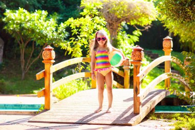 Havuzda şişme oyuncak topu olan bir çocuk. Çocuklar yüzer. Genç çocuklar için renkli gökkuşağı yüzüyor. Küçük kız yaz tatilinde tropikal tatil köyünde eğleniyor. Kumsal ve su eğlencesi. 