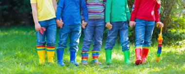 Çizmeli çocuklar. Renkli lastik çizmeler ve sonbahar ceketleri giymiş bir grup anaokulu çocuğu. Yağmurlu bir sonbahar için ayakkabılar. Çocuk ve bebek için ayak giysisi. Çizmeli yeni yetme. Gökkuşağı çizmeleri. Çocuk modası
