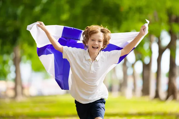 stock image Child running with Finland flag. Little Finnish boy cheering for football team. Suomi fans on soccer pitch watching team play. Family celebrating national day. Championship game.