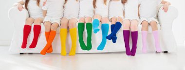 Renkli gökkuşağı çorapları giyen çocuklar. Çocuk ayakkabısı koleksiyonu. Diz boyu çorap ve tayt çeşitleri. Çocuk giysisi ve giysisi. Çocuk modası. Küçük erkek ve kız grubunun bacakları ve ayakları.