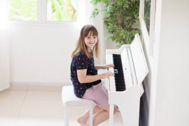Piyano çalan çocuk. Çocuklar müzik çalar. Çocuklar için klasik eğitim. Sanat dersi. Beyaz dijital klavyede küçük bir kız. Genç öğrenciler için bir araç. Okulda ya da evde müzik dersi.