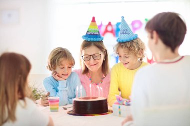 Çocukların doğum günü partisi. Çocuk pastaya mum üflüyor ve hediyeleri açıyor. Pastel gökkuşağı temalı kutlama. Aile evde kutlama yapıyor. Oğlan ve kız hediyeleri açar, pasta yerler. Çocuklar için tatlılar.