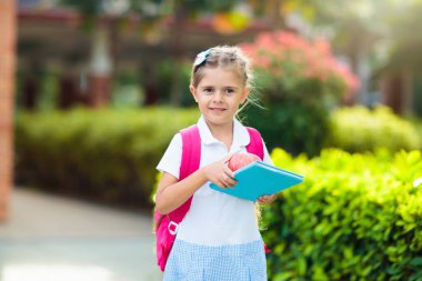 Çocuk okula geri dönüyor. Yaz tatilinden sonraki yıl yeni bir okula başlıyorum. İlk okul gününde sırt çantası ve kitapları olan küçük bir kız. Dersin başında. Anaokulu ve anaokulu çocukları için eğitim.