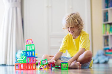 Çocuk manyetik yapı taşlarıyla oynuyor. Küçük çocuk kule inşa ediyor. Çocuklar için eğitici oyuncaklar. Küçük çocuklar için inşaat oyuncakları. Geometri ve matematik oyunu. Okul öncesi eğlencesi.