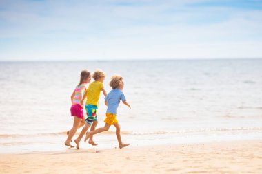 Tropik plajda oynayan bir çocuk. Deniz kıyısında elinde kova ve kürek olan küçük bir çocuk. Aile yaz tatili. Çocuk kumdan kale yapıyor. Çocuklar için su ve kum eğlencesi. Çocuklar oynar, okyanus kıyısında kale yaparlar.