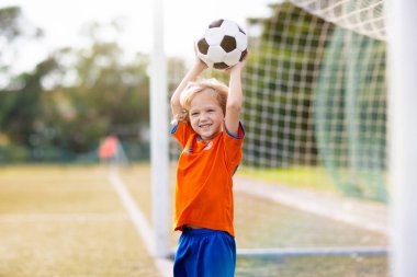 Hollandalı çocuklar dışarıda futbol oynarlar. Hollanda milli bayrağı olan takım taraftarları. Bastır Hollanda! Çocuklar futbol maçında gol attılar. Bayrak formalı çocuk topa vuruyor. Taraftarlar sahada zaferi kutluyor