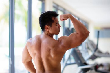 Spor salonunda egzersiz yapan bir adam. Asyalı vücut geliştirici ağırlık kaldırıyor. Genç bir erkek için spor ve sağlıklı aktivite. Eğitimdeki aktif Çinli atlet. Vücut geliştirme egzersizi..