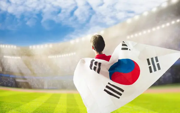 stock image South Korea football supporter on stadium. Korean fans on soccer pitch watching team play. Group of supporters with flag and national jersey cheering for the Republic of Korea. Championship game.