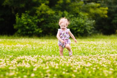 Pembe elbiseli şirin küçük bir kız çiçek açan bahar parkında ilk beyaz yaban şakayığı çiçeğiyle oynuyor. Paskalya yumurtası avına çıkmış bir çocuk. Çocuklar açık havada çiçek buketi topluyor..