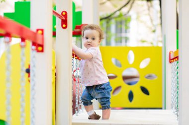Güneşli bir yaz gününde parkta oynayan bir çocuk. Çocuklar sallanıyor ve kayıyor. Okul ya da anaokulu bahçesi ve oyun alanı. Yazın açık hava aktivitesi. Oynayan çocuk.
