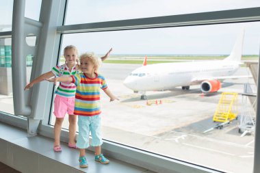 Havaalanındaki çocuklar. Çocuklar uçağa bakın. Çocukla seyahat ve uçmak. Aile çıkış kapısında. Tatil ve küçük çocukla seyahat. Uçuştan önceki çocuk. Çocuklar uçak uçurur..