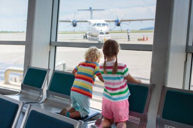 Havaalanı'nda çocuklar. Çocuk uçağa bak. Seyahat ve çocuk ile uçan. Aile kalkış kapısı. Tatil ve seyahat genç çocukla. Erkek ve kız Terminal uçuş öncesi. Çocuklar uçak.