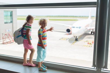 Havaalanındaki çocuklar. Çocuklar uçağa bakın. Çocukla seyahat ve uçmak. Aile çıkış kapısında. Tatil ve küçük çocukla seyahat. Uçuştan önceki çocuk. Çocuklar uçak uçurur..