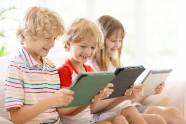 Cep telefonu olan çocuklar. Tabletli çocuk film izliyor ya da oyun oynuyor. Dijital cihazı ve aleti olan bir grup küçük çocuk. Küçük çocuk için ekran zamanı ve eğitim. Arkadaşlar oynar.