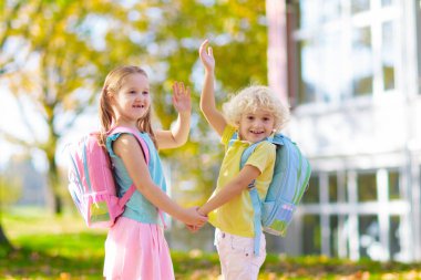 Çocuklar okula geri döner. Yaz tatilinden sonraki yıl yeni bir okula başlıyorum. İlk okul gününde sırt çantası ve kitapları olan kız ve erkek. Dersin başında. Anaokulu ve anaokulu çocukları için eğitim.