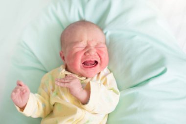 Yeni doğmuş bebek hastane odasında, hemşire yastığının üzerinde. Beşikte yeni doğmuş bir çocuk. Yatağın başucunda aç bir bebek var. Küçük çocuk doğumdan hemen sonra banyo ve muayeneden sonra.
