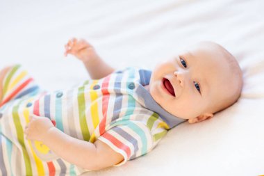 Beyaz güneşli yatak odasında sevimli bir bebek. Yeni doğmuş çocuk yatakta dinleniyor. Küçük çocuklar için çocuk odası. Çocuklar için tekstil ve yatak. Aile sabahı evde. Oyuncak ayıyla karnını doyururken doğan yeni çocuk..